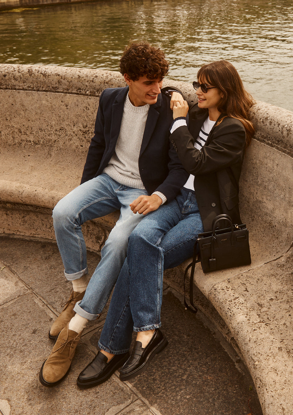 EDITORIAL IMAGE OF TWO MODELS SITTING. FIRST MODEL IS WEARING LARK COAT, DONOVAN SWEATER, AND CLAYTON SLIM STRAIGHT JEANS. SECOND MODEL IS WEARING JAC BLAZER, GEMMA SWEATER, AND TOPANGA STRAIGH JEANS