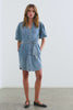 Video of woman wearing a light blue mini denim dress with a tied belt attached. Woman is spinning in video