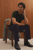 Ezra Pant in Brushed Cotton Twill With Relaxed Fit, Single Front Pleats, Ankle-Length Hem, Zip Fly, Side Pockets, and Back Double-Welt Pockets in Black Colorway - Video - Front View Featured on Sitting Model.