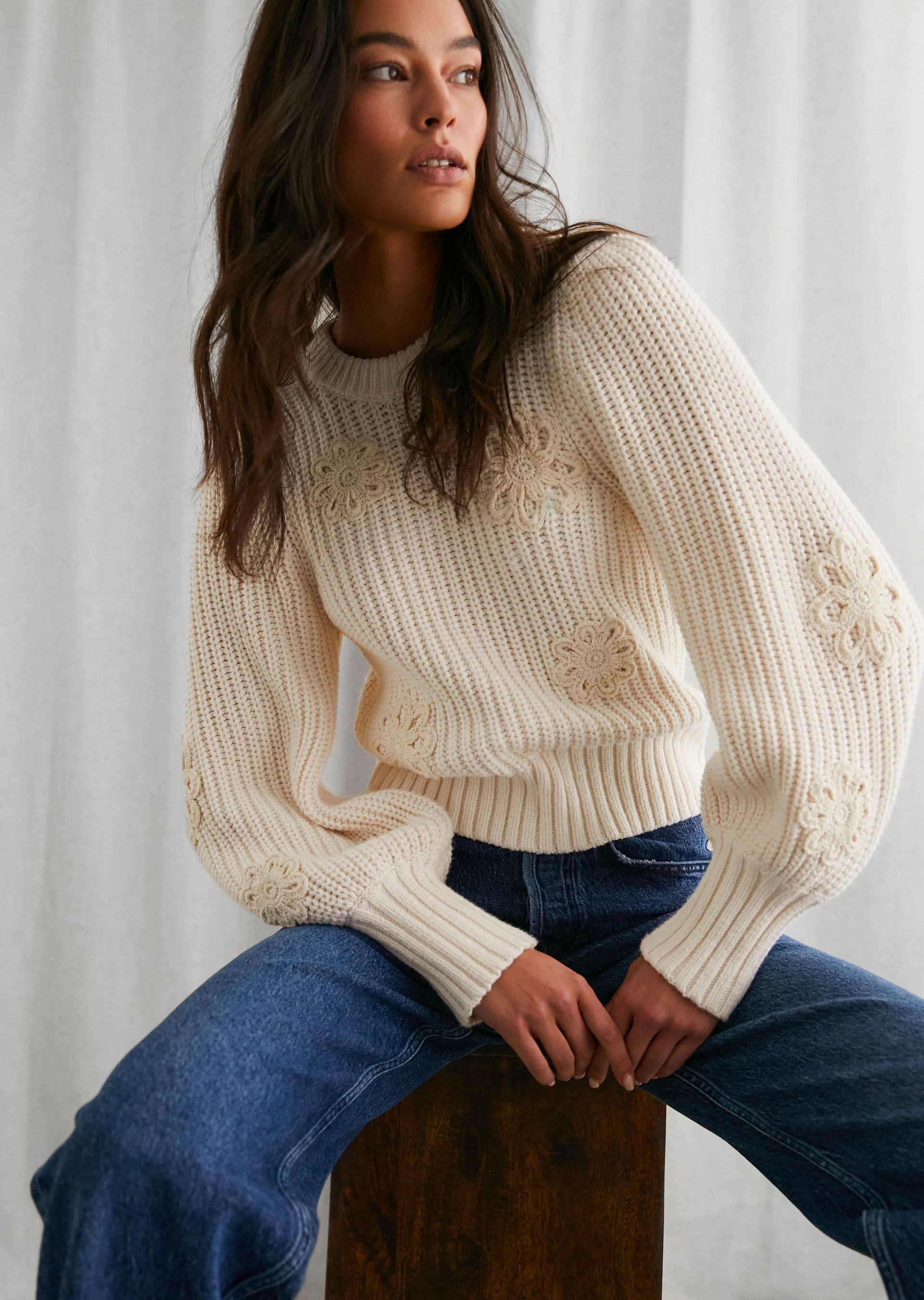 FRONT EDITORIAL IMAGE OF MODEL SITTING WEARING ROMY SWEATER AND GETTY WIDE LEG JEANS