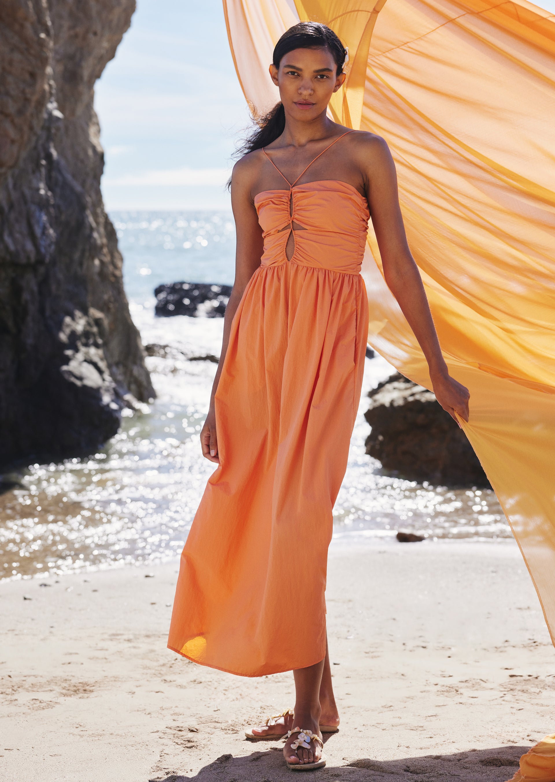 FRONT FULL BODY EDITORIAL IMAGE OF MODEL ON THE BEACH WEARING SILVIA DRESS IN PAPAYA