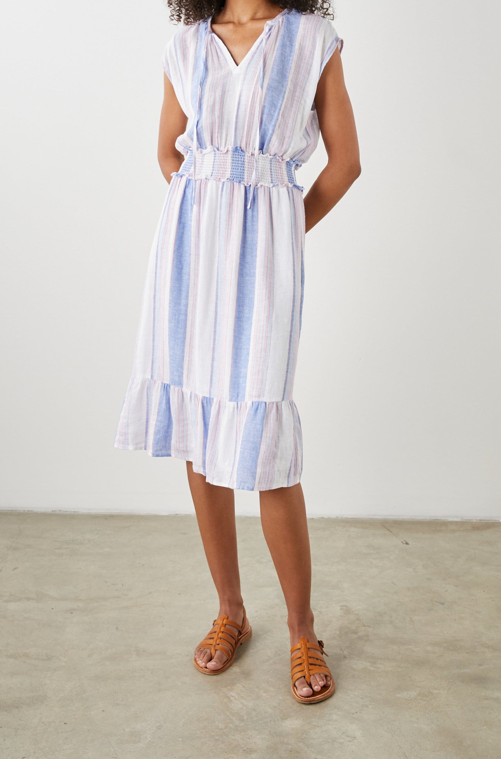 Ashlyn Short Sleeve Midi Dress with a V neck with Ties, a Smocked Waist and a Ruffle Tier at the Hem in Marini Stripe Colorway, Vertical Stripes in Pink and Blue on White - Front Full Body View Featured on Model