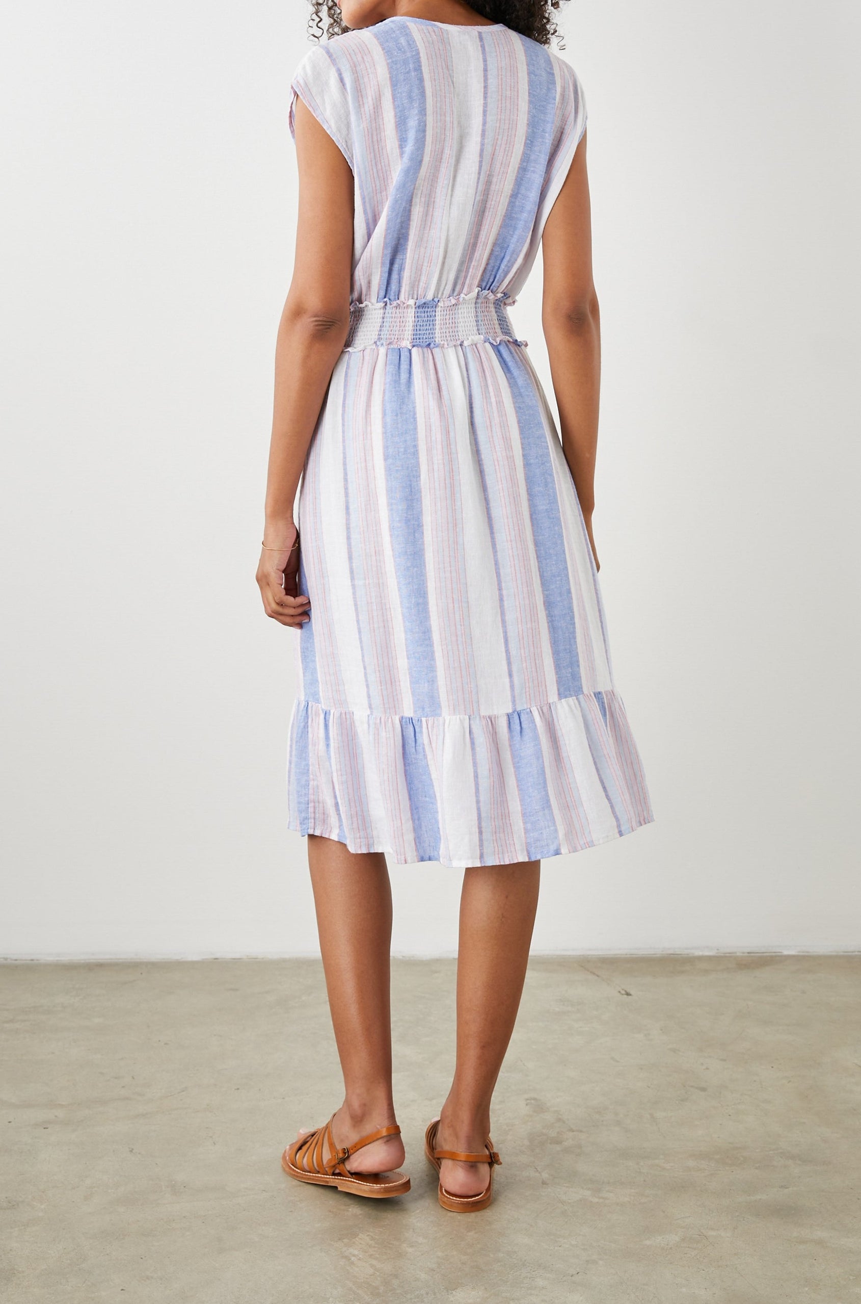 Ashlyn Short Sleeve Midi Dress with a V neck with Ties, a Smocked Waist and a Ruffle Tier at the Hem in Marini Stripe Colorway, Vertical Stripes in Pink and Blue on White - Back Full Body View Featured on Model