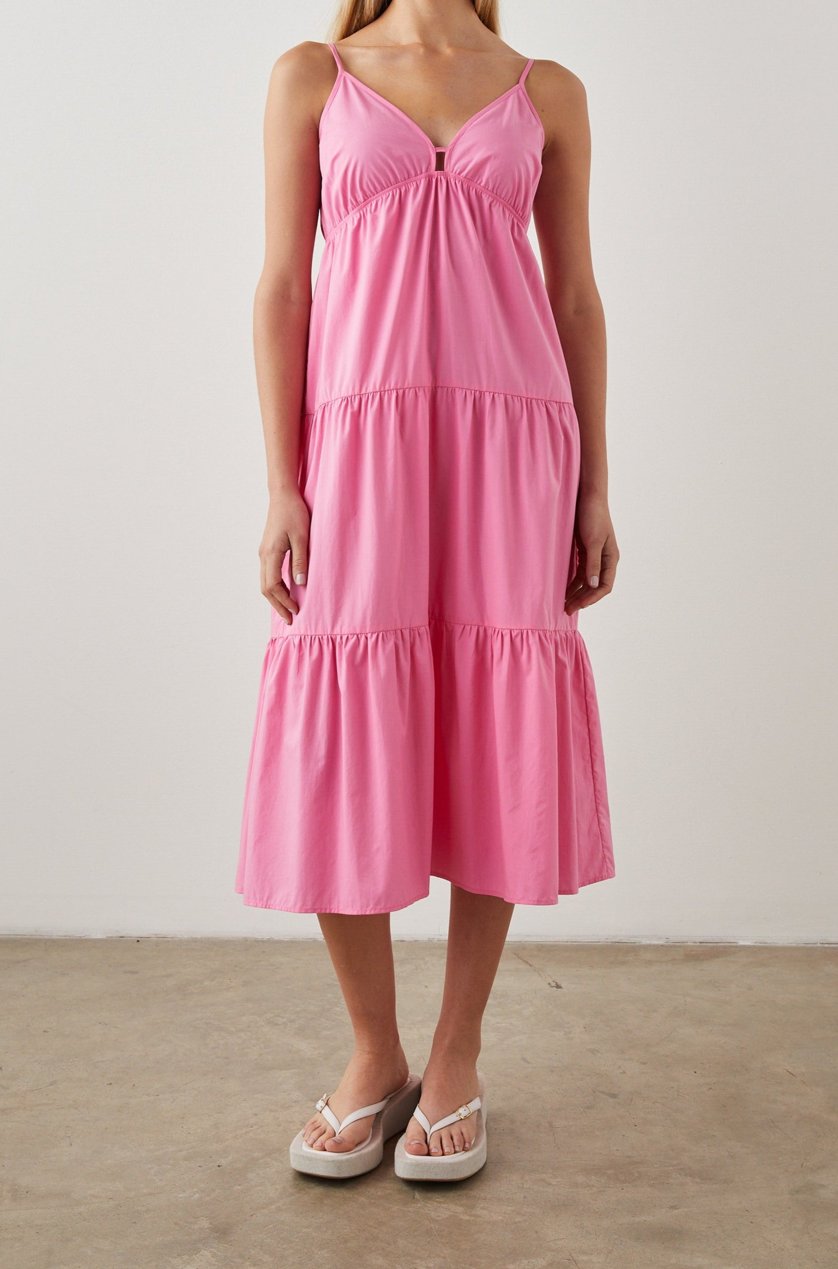 Avril Sleeveless, Tiered Midi Dress with Adjustable Spaghetti Straps, a V Neck with a Cutout and Light Ruching at Each Tier Seam in Hot Pink Colorway - Front Full Body View Featured on Model 