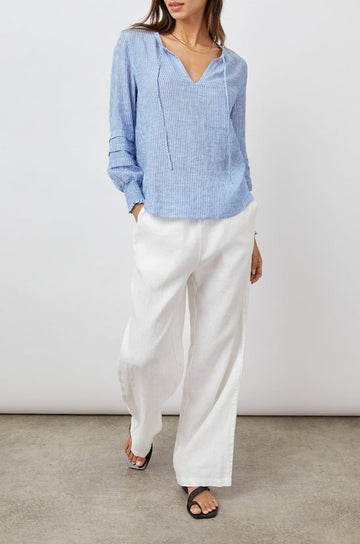 Caterina Long-Sleeve Top with a V neck, Neck Ties, Shirred Cuffs and Horizontal Pleats on the Sleeves in Sanibel Stripe Colorway, Thin White and Blue Vertical Stripes - Front Full Body View Featured on Model