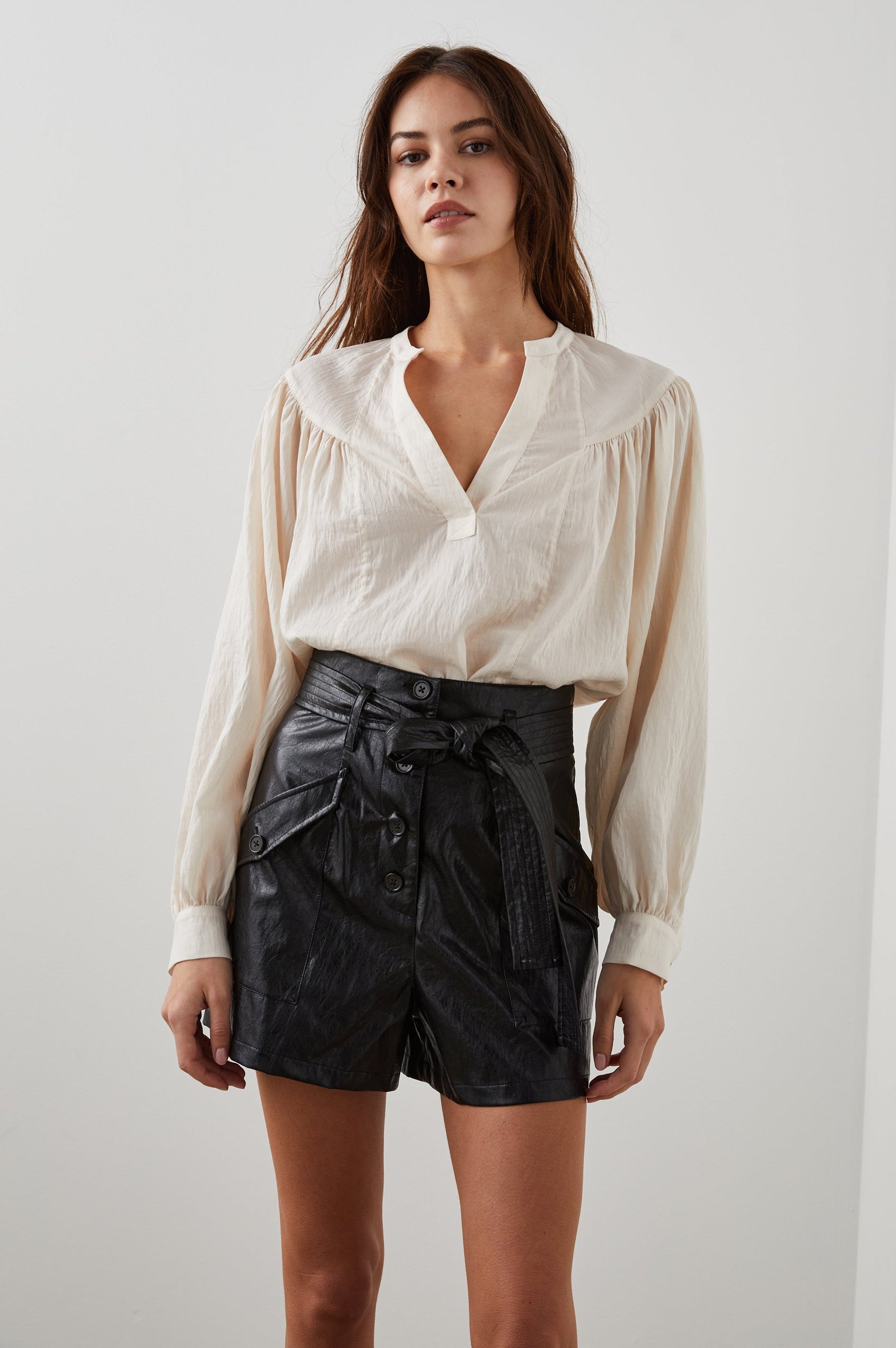 Fable Long Sleeve Top with a V Neck with a Placket, Buttoned Cuffs, and Pleating Down From the Yoke in Lotus Colorway - Front Tucked View Featured on Model 