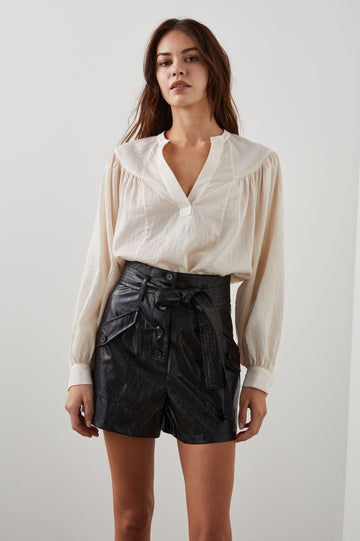 Fable Long Sleeve Top with a V Neck with a Placket, Buttoned Cuffs, and Pleating Down From the Yoke in Lotus Colorway - Front Tucked View Featured on Model 