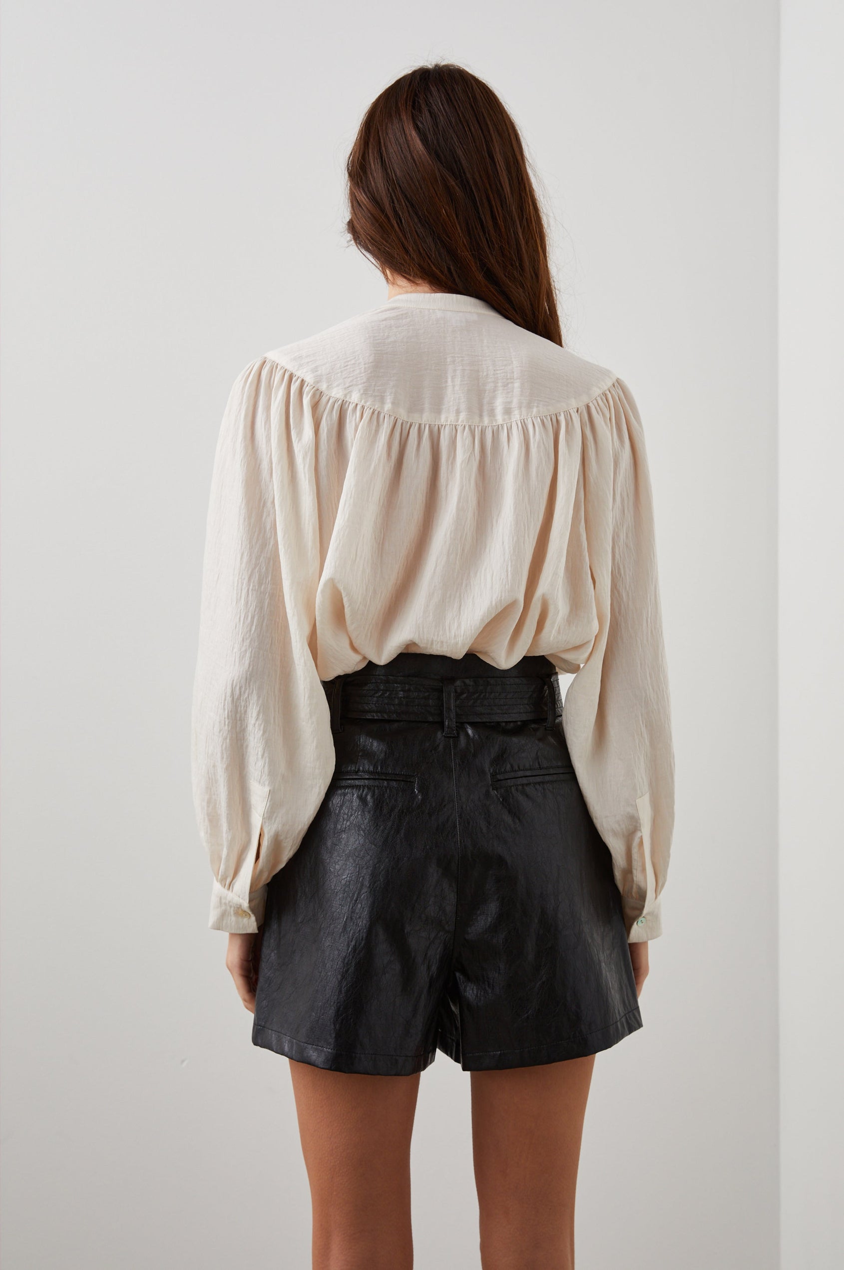 Fable Long Sleeve Top with a V Neck with a Placket, Buttoned Cuffs, and Pleating Down From the Yoke in Lotus Colorway - Back View Featured on Model 