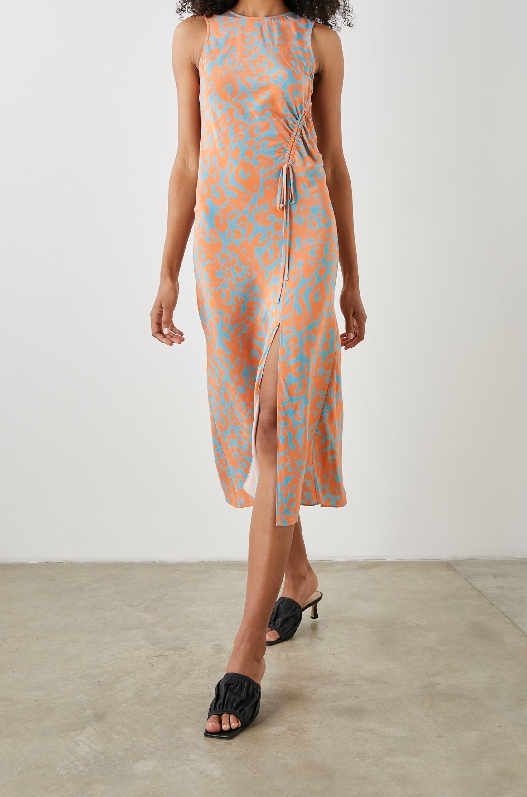 Gabriella Sleeveless Midi Dress with a Crew Neck, a Left Thigh Side Slit, a Ruched Drawstring on the Left Side and a Keyhole Button Closure at the Back in Orange Diffused Cheetah Colorway, Orange Spots on Blue - Front Full Body View Featured on Model 