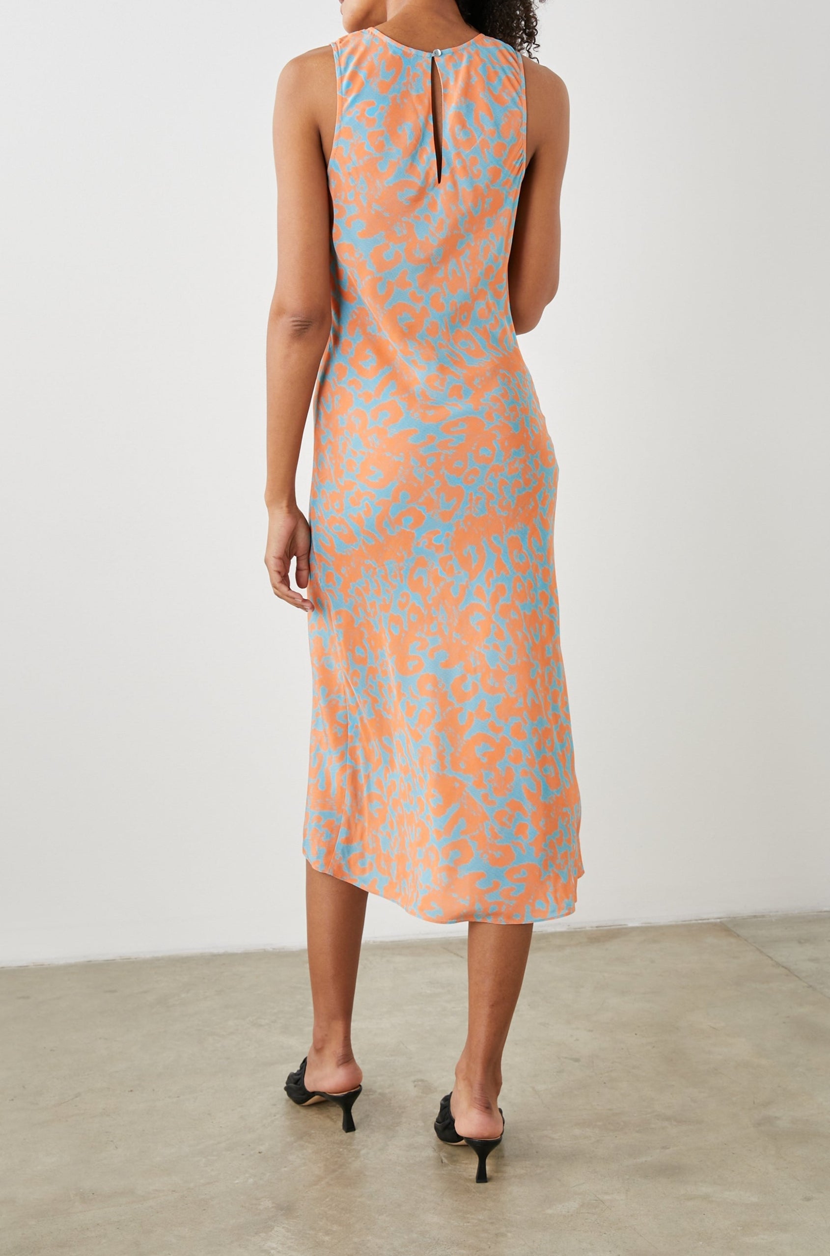 Gabriella Sleeveless Midi Dress with a Crew Neck, a Left Thigh Side Slit, a Ruched Drawstring on the Left Side and a Keyhole Button Closure at the Back in Orange Diffused Cheetah Colorway, Orange Spots on Blue - Back Full Body View Featured on Model 