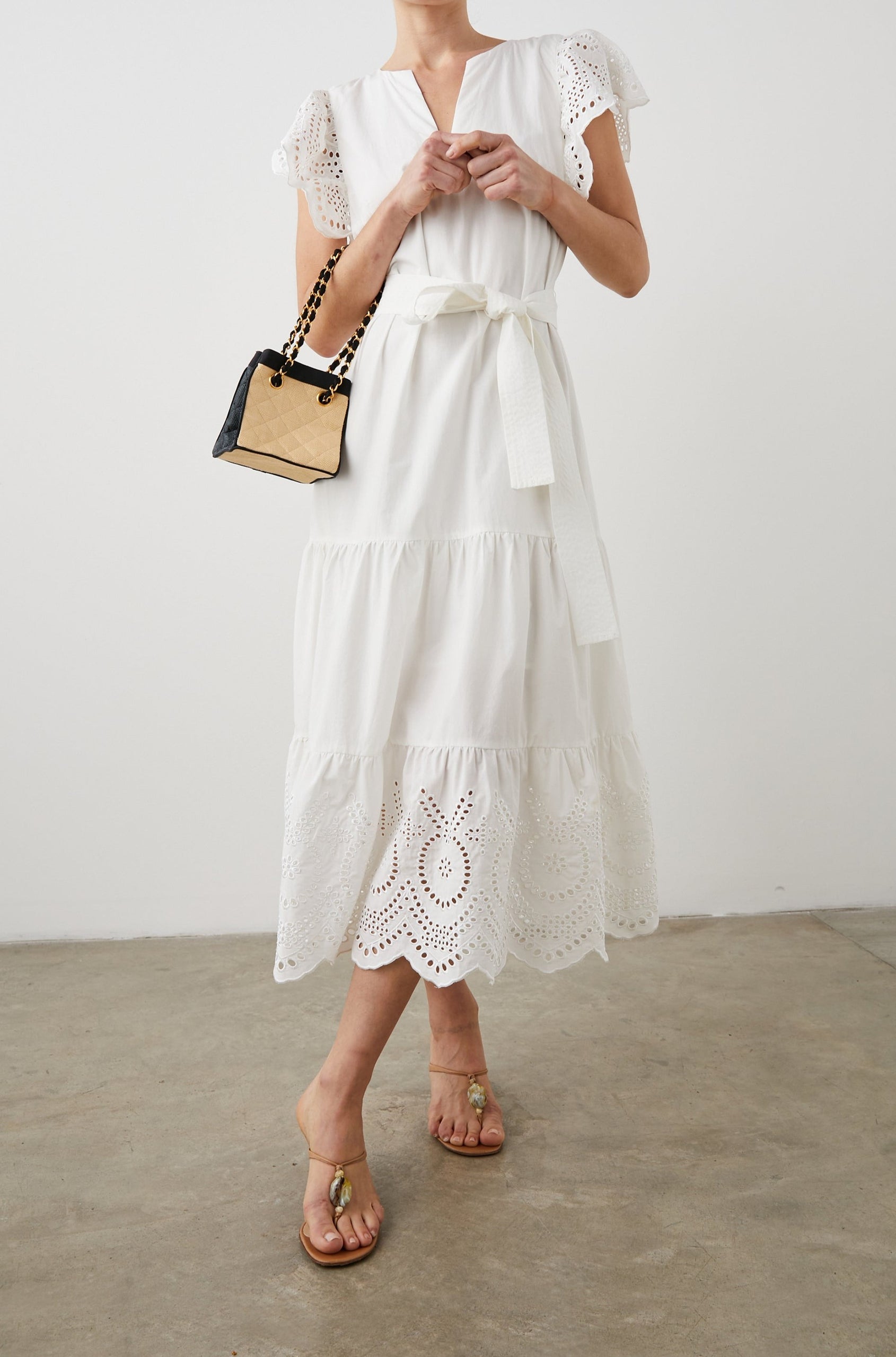 Gia Short-Sleeve Midi Dress with Flutter Sleeves, a V Neck, a Fabric Tie at the Waist, a Tiered Skirt and Eyelet Detail on the Sleeves and Hem in White Colorway - Front Full Body View Featured on Model
