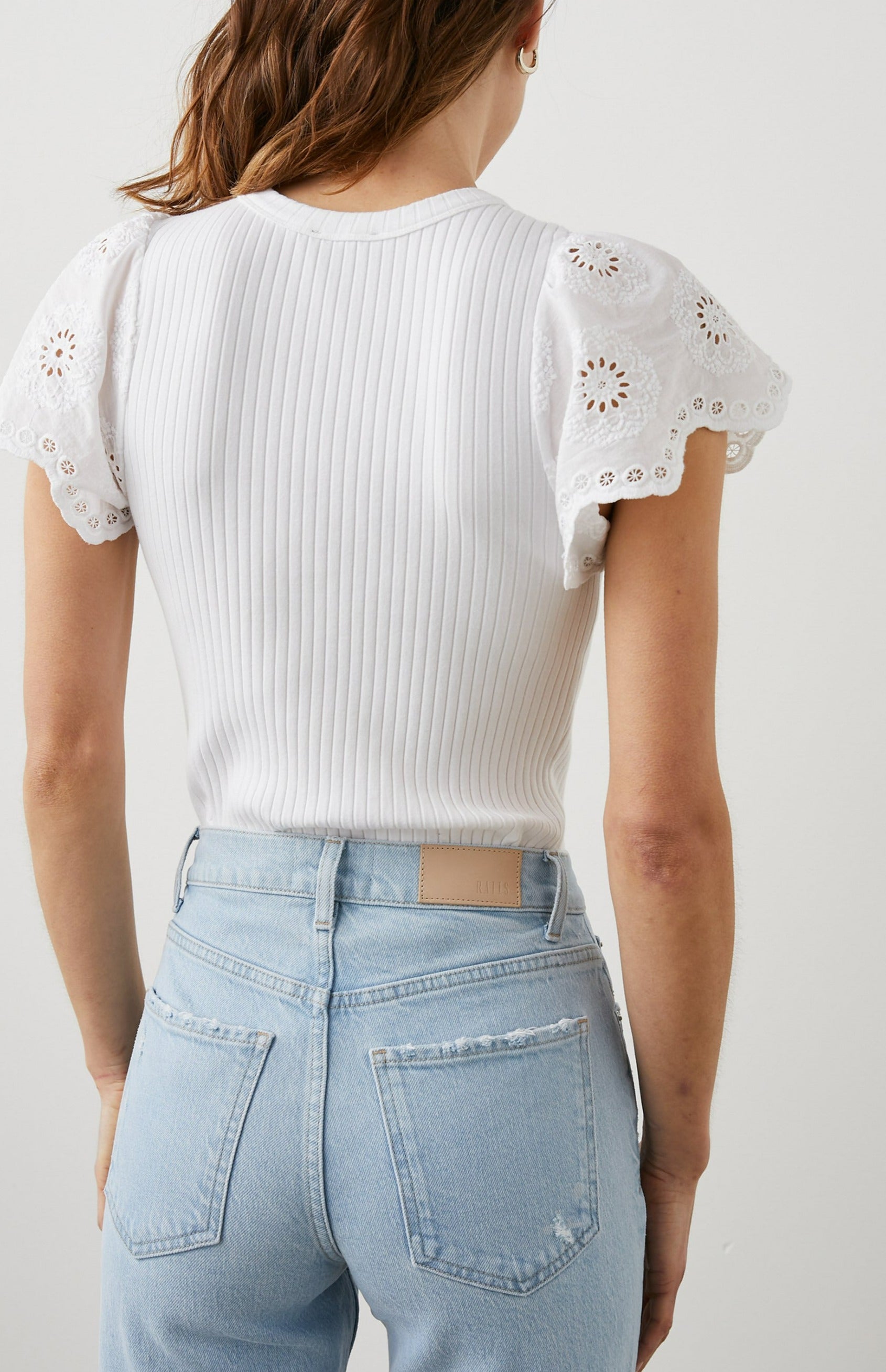 Reza Ribbed Short Sleeve Top with Flutter Sleeves, a Crew Neck and Floral Eyelets on the Sleeves in White Colorway - Back Tucked View Featured on Model 