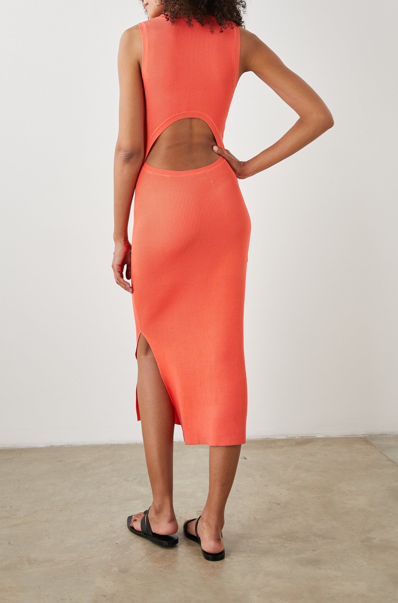 Syd Ribbed, Sleeveless Midi Dress with Wide Shoulder Straps, a Side Slit, and a Cutout that Spans the Lower Back in Black Colorway - Back Full Body View Featured on Model  